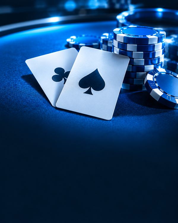 Dos cartas y una pila de fichas sobre un tapete azul bajo luz fría